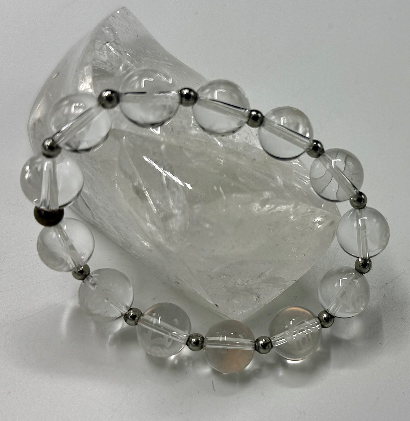 Quartz bracelet with carved prayer symbols, crafted by STICS and STONES, featuring polished beads and detailed carvings.