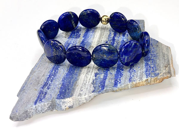 Round flat Lapis Lazuli bracelet by STICS and STONES featuring deep blue stones with gold-toned accents and adjustable cord.