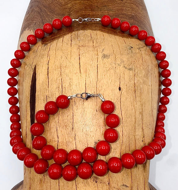 Red pearl jewelry set featuring a necklace and bracelet by STICS and STONES, displayed on a neutral background.
