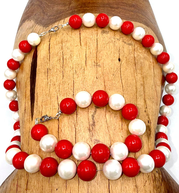 Red and pearl jewelry set featuring a necklace and bracelet from STICS and STONES, with matching pearls and vibrant red accents.
