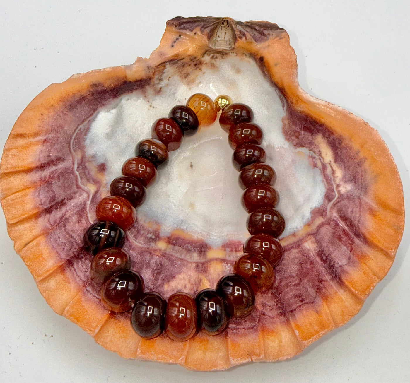 Carnelian bracelet featuring polished orange-red stones from STICS and STONES, displayed on a neutral background.
