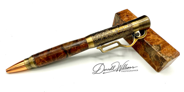 Hand-turned Gmelina burl wood rifle pen by STICS and STONES, showcasing polished wood and fine craftsmanship.