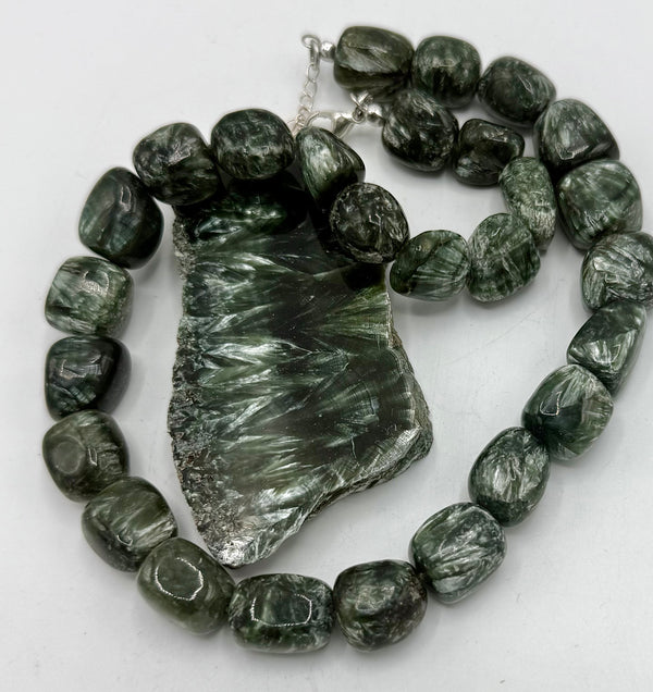 Seraphinite necklace by STICS and STONES featuring a polished green gemstone pendant on a silver chain.