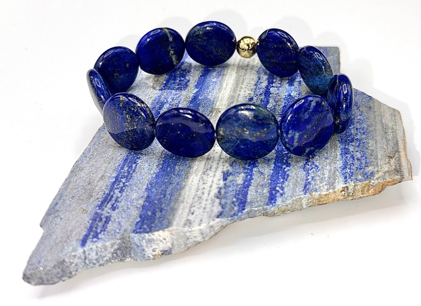 Round flat Lapis Lazuli bracelet by STICS and STONES featuring deep blue stones with gold-toned accents and adjustable cord.