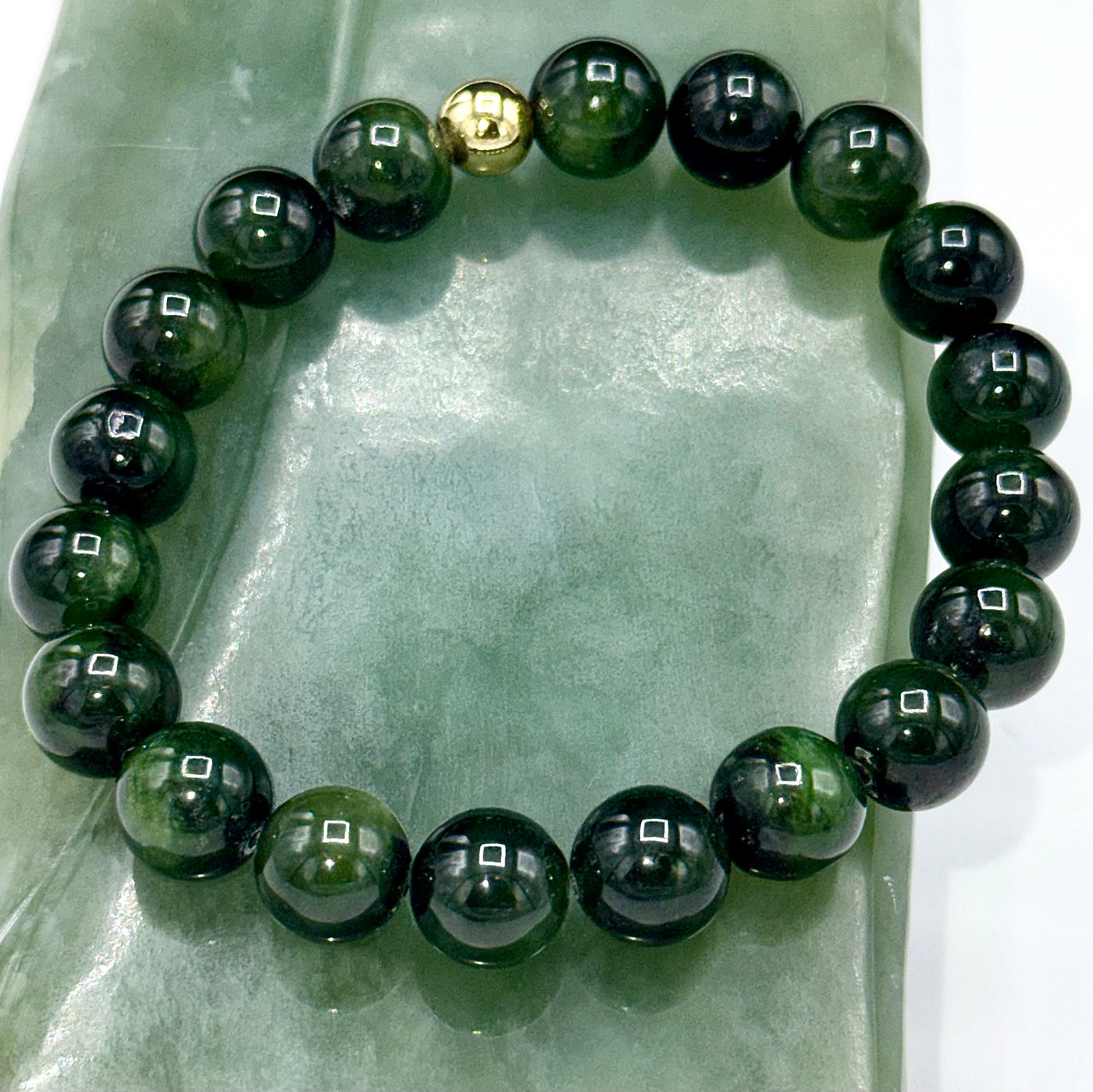 Nephrite jade bracelet with polished green stones on a string, crafted by STICS and STONES.