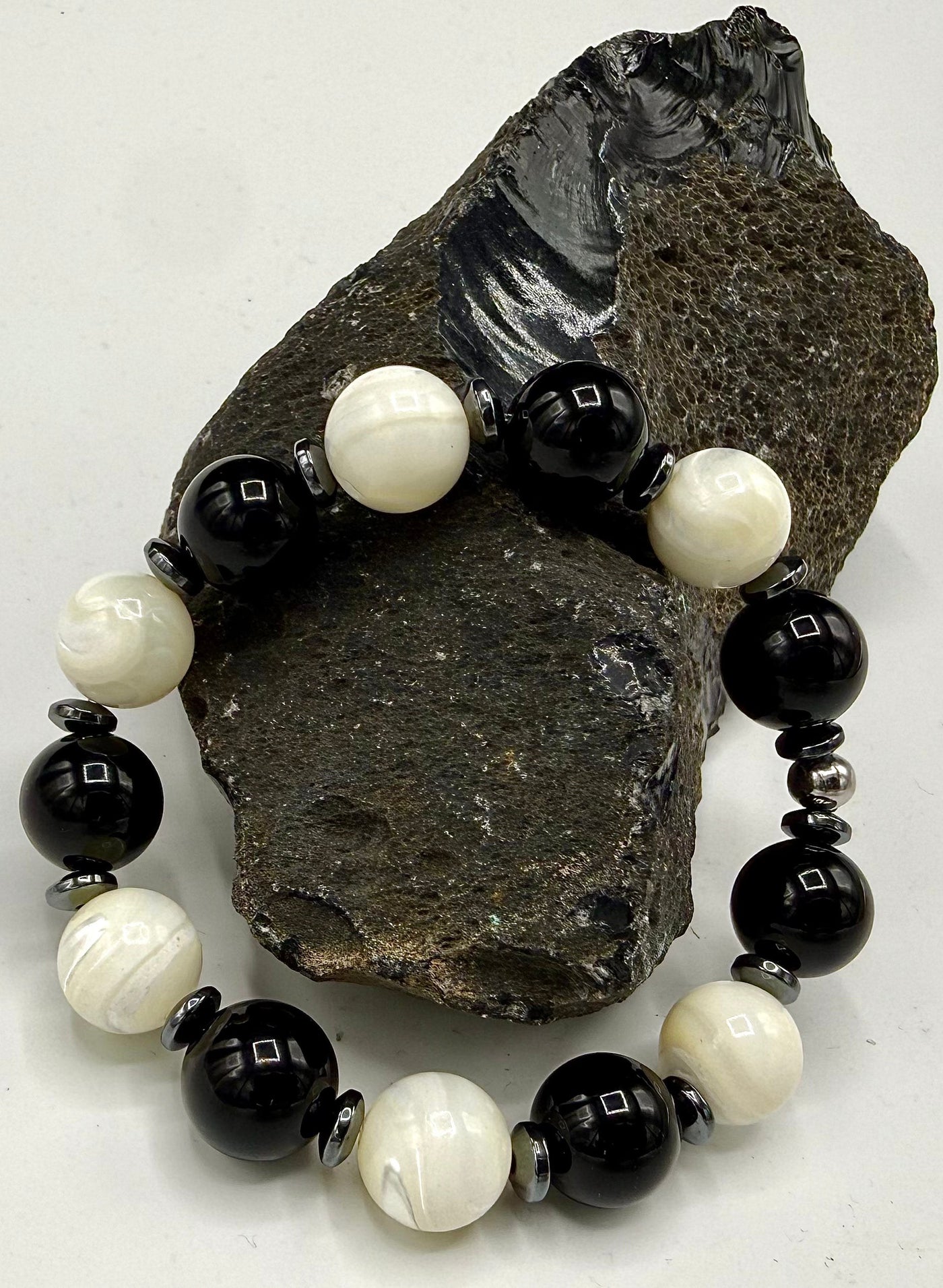 Faceted hematite, onyx, and pearl bracelet featuring polished beads from STICS and STONES, showcasing elegant, mixed gemstone design.