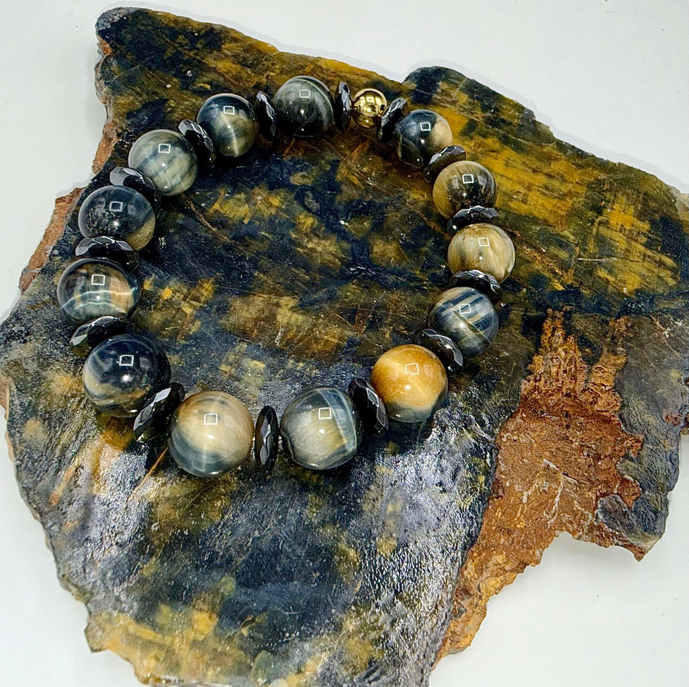 Black, gold, and grey tiger eye bracelet from STICS and STONES featuring polished tiger eye beads on an elastic band.