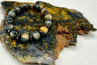 Black, gold, and grey tiger eye bracelet by STICS and STONES featuring polished tiger eye beads on an elastic band.