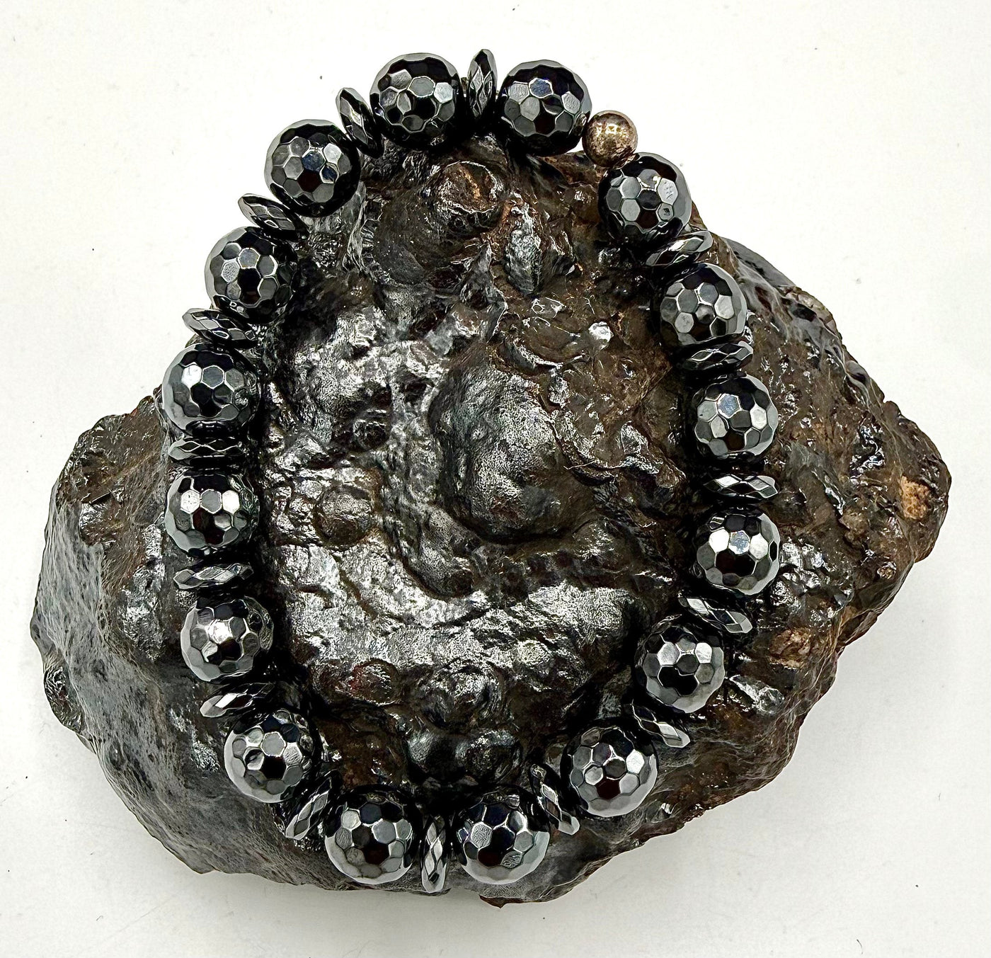 Faceted hematite bracelet from STICS and STONES featuring glossy, dark metallic beads on an elastic band.