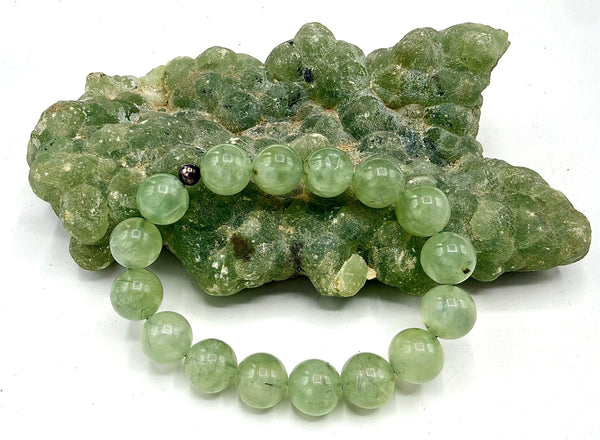 Prehnite bracelet featuring smooth green stones on a string, crafted by STICS and STONES, displayed on a neutral background.
