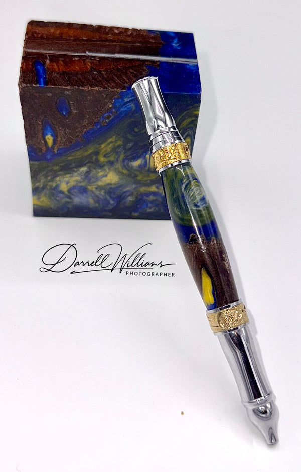Hand-turned blue and gold acrylic and dark wood pen by STICS and STONES, showcasing a sleek, elegant writing instrument.